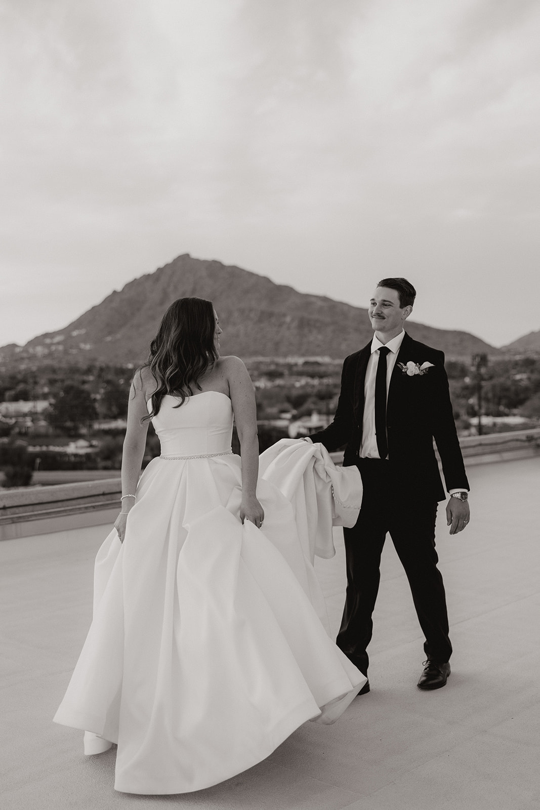 bride looks back at groom while he holds her wedding dress train after Hotel Valley Ho wedding