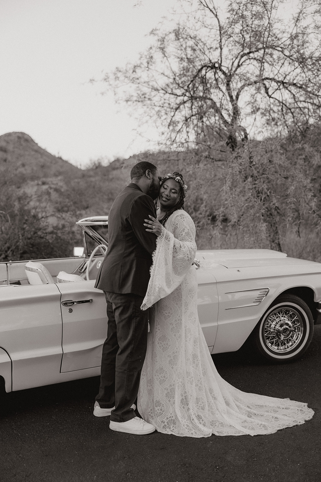 stunning couple embrace beside a vintage convertible 