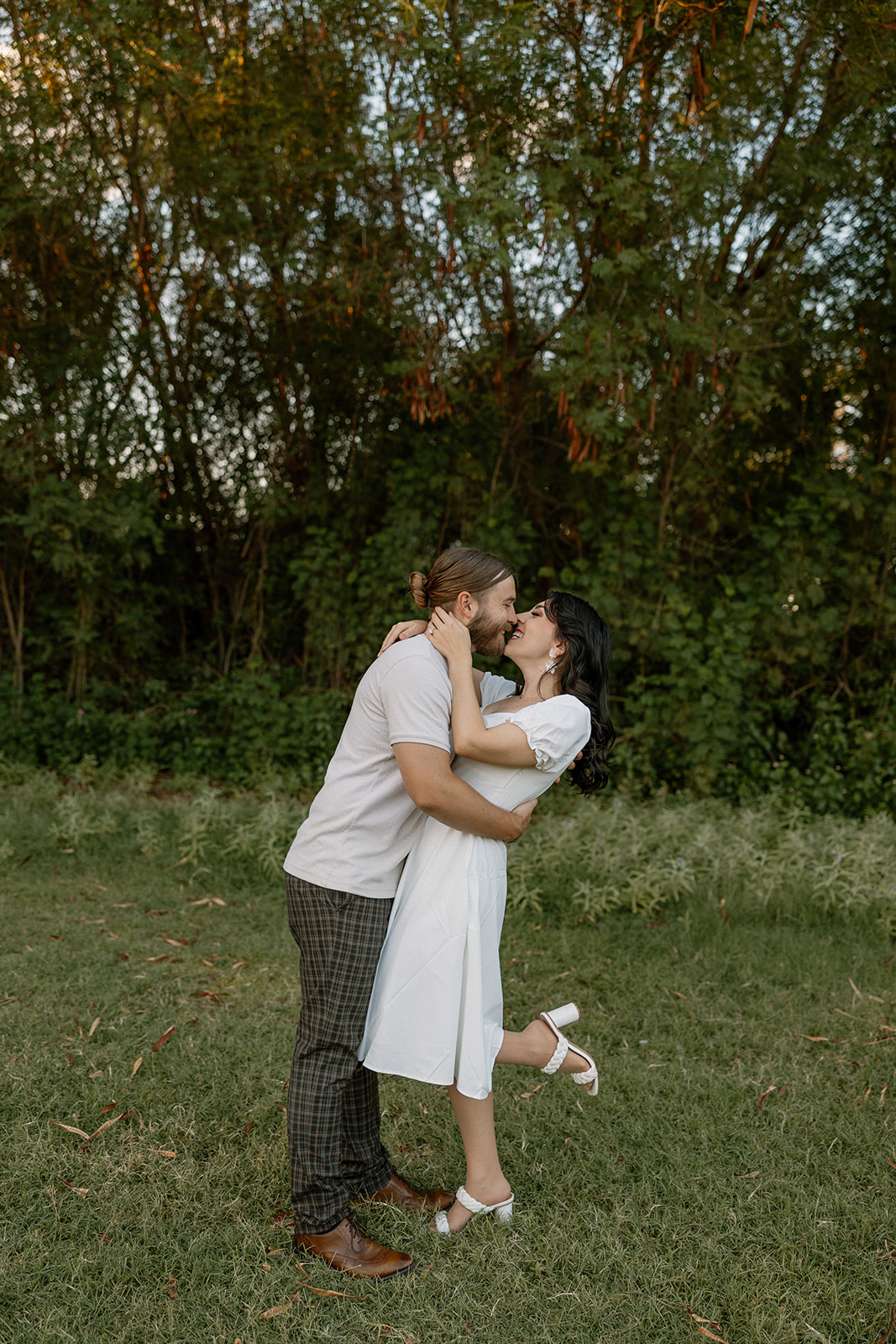 beautiful couple share a romantic kiss together in the greenery during their Mesa Arizona Engagement Photos
