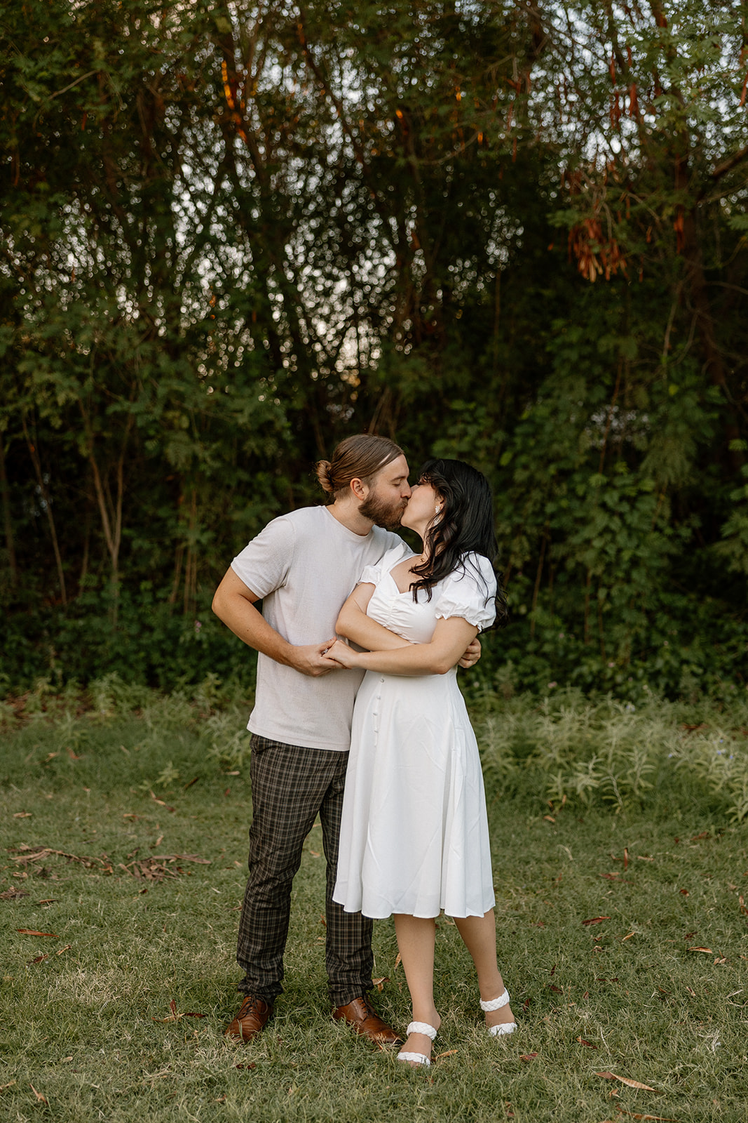 beautiful couple share a romantic kiss together in the greenery during their Mesa Arizona Engagement Photos