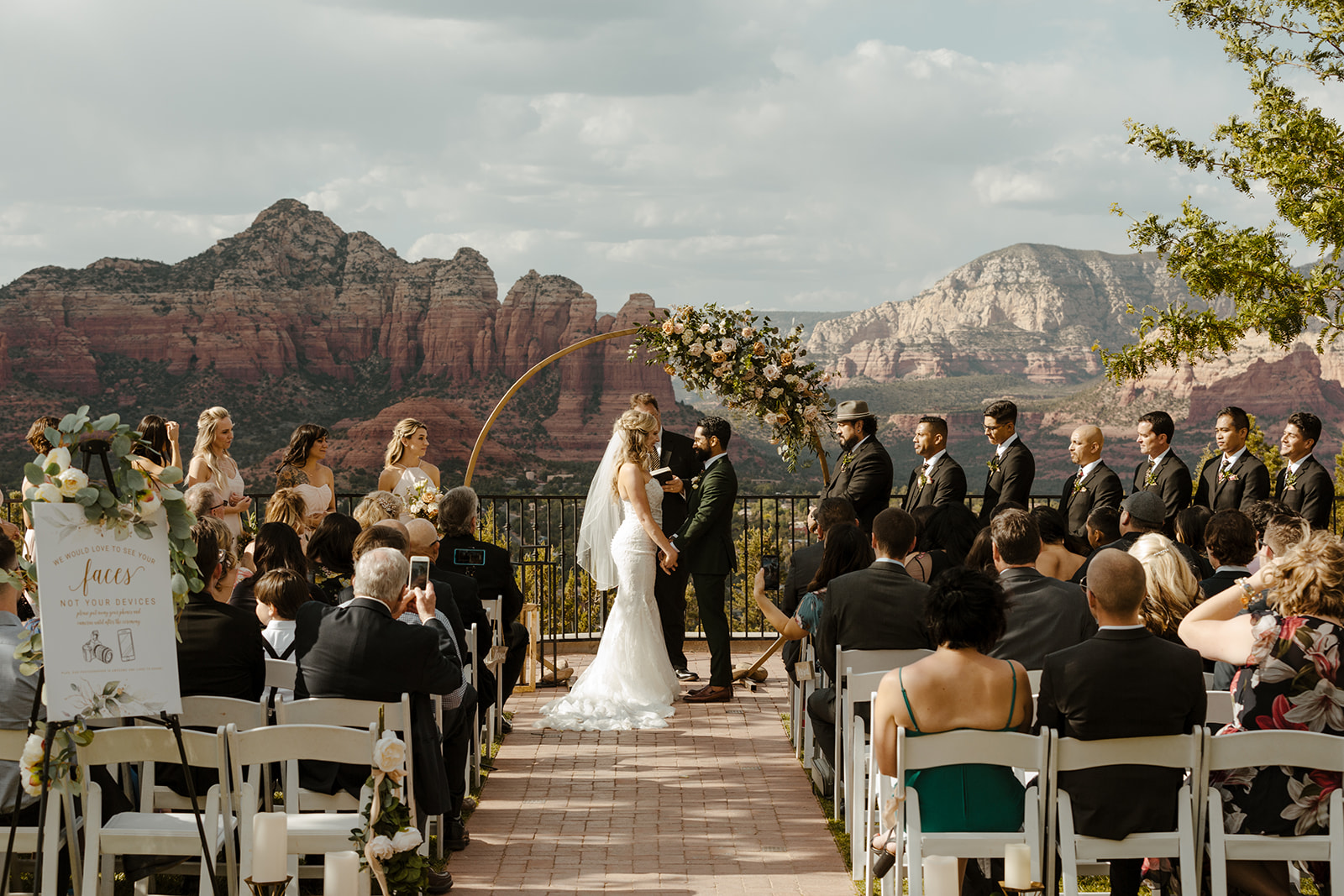 Couple holding hands at altar with beautiful red rock views behind them