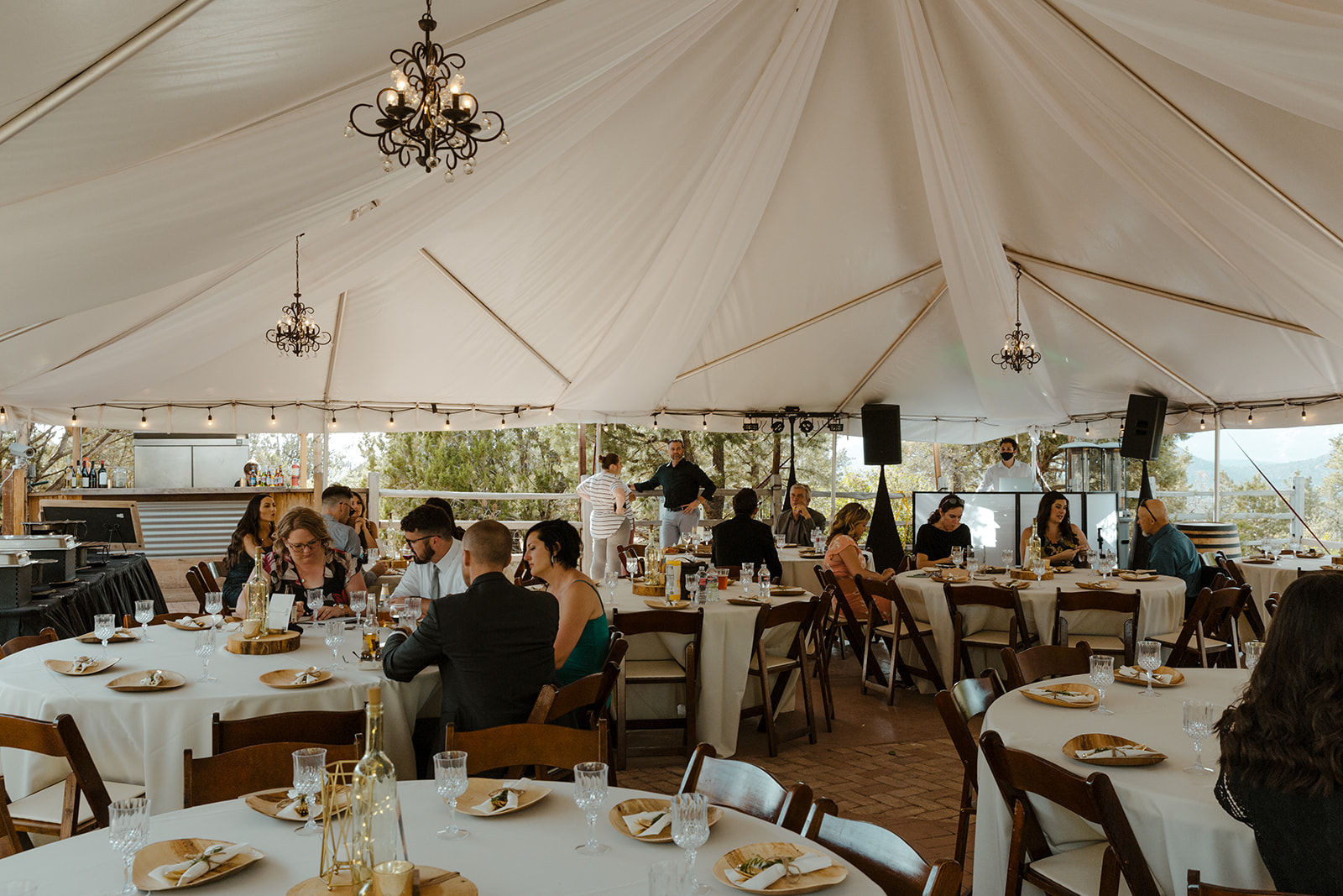 Tented indoor reception with guests getting seated for dinner