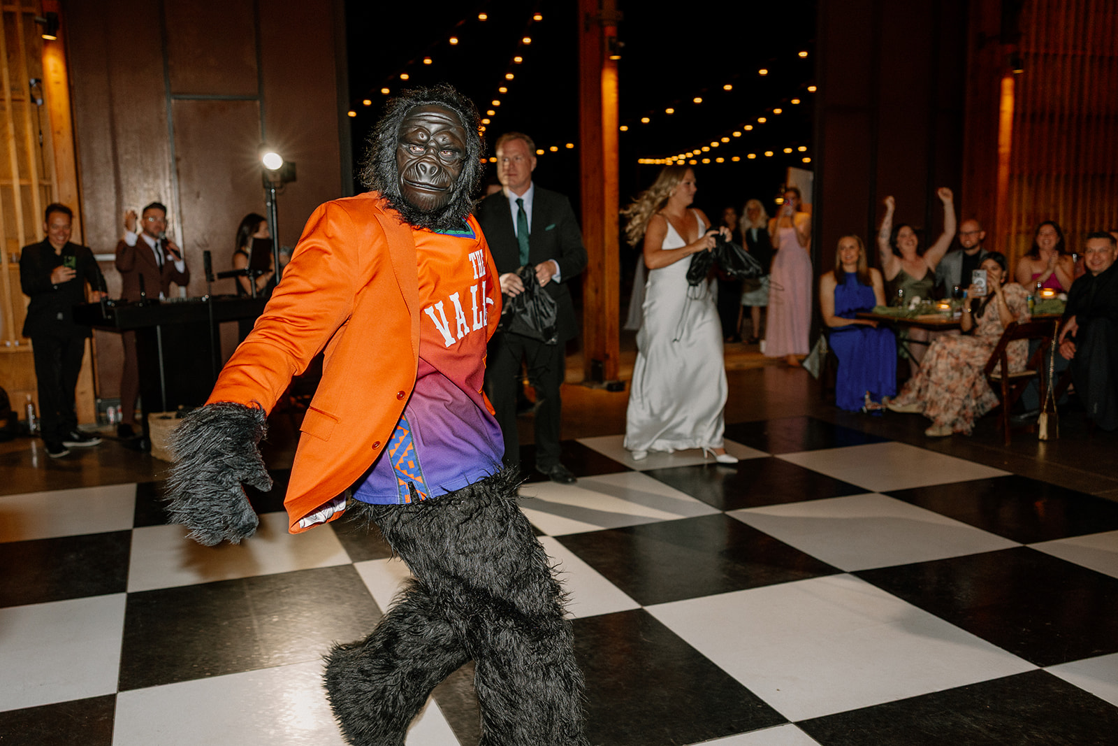 A performer in a gorilla suit and Suns jersey hypes up the crowd on the black-and-white dance floor at a bold Arizona wedding reception.
