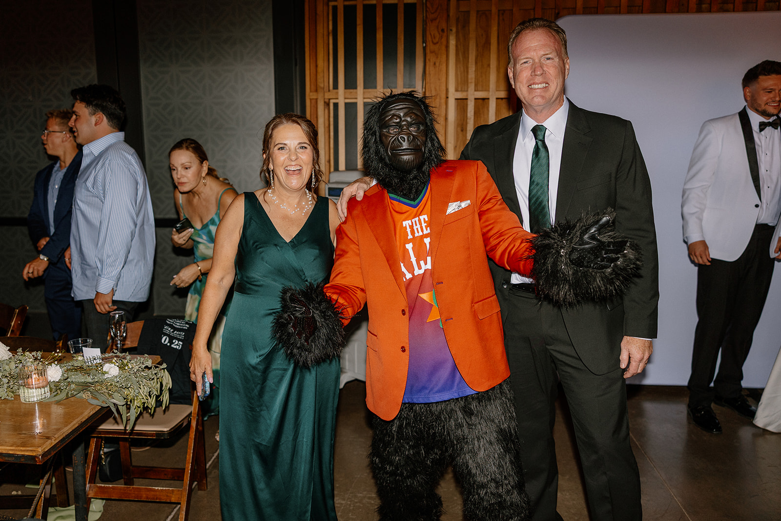 Guests pose with a performer in a gorilla costume wearing a Phoenix Suns jersey during a playful moment at the wedding reception.

