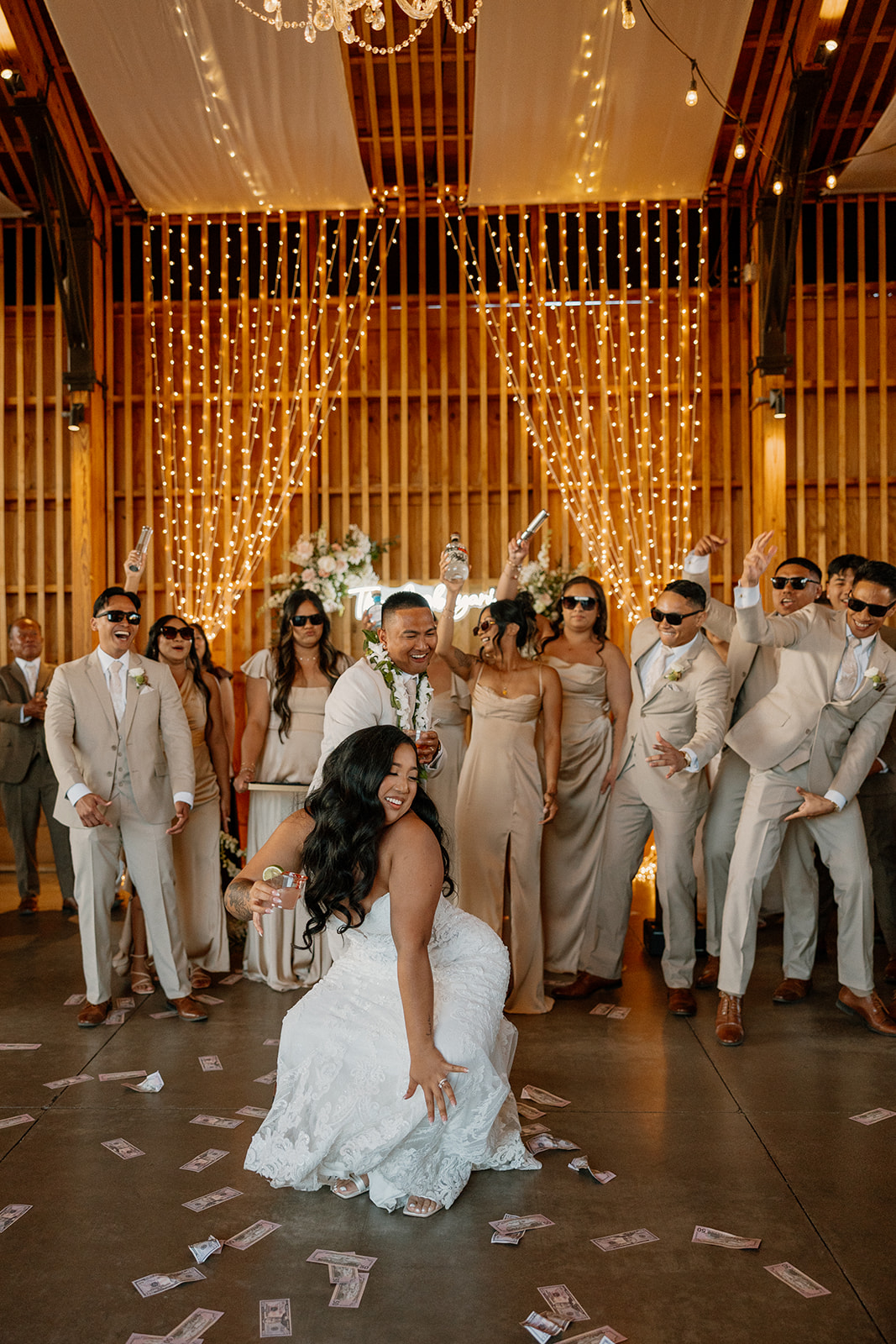 The wedding party throws money while the bride drops it low on the dance floor at an indoor Arizona wedding reception.

