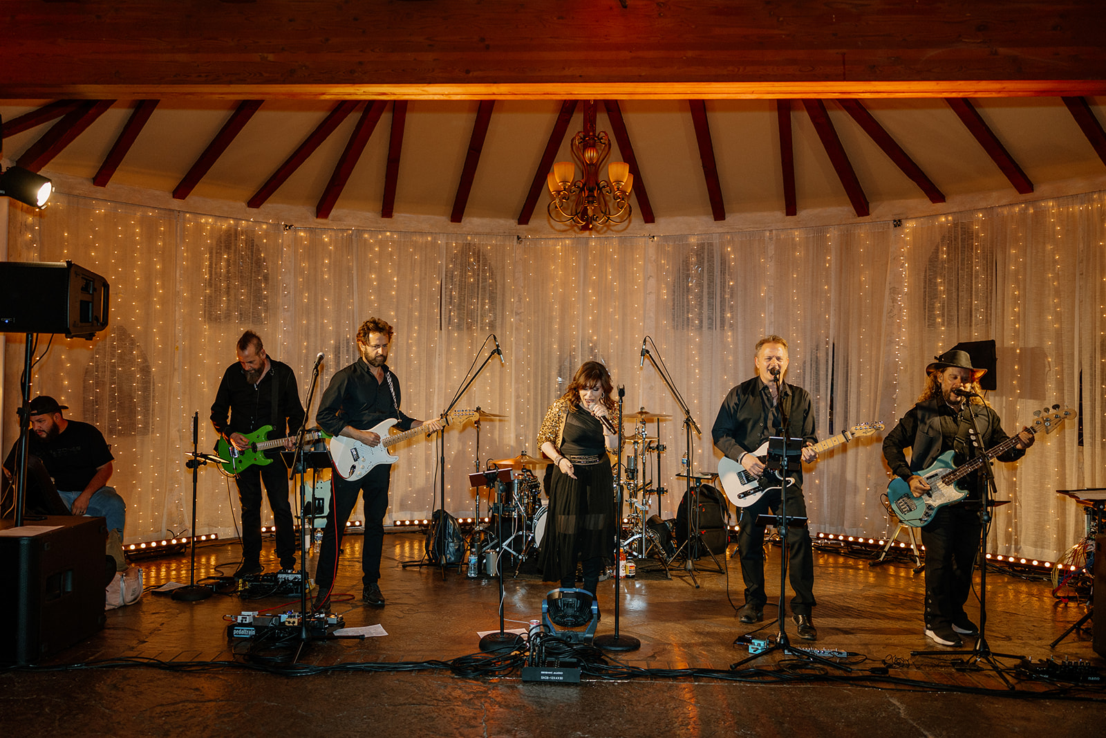 A live wedding band performs beneath romantic curtain lights at an indoor venue, adding a classic vibe to the Arizona wedding reception.
