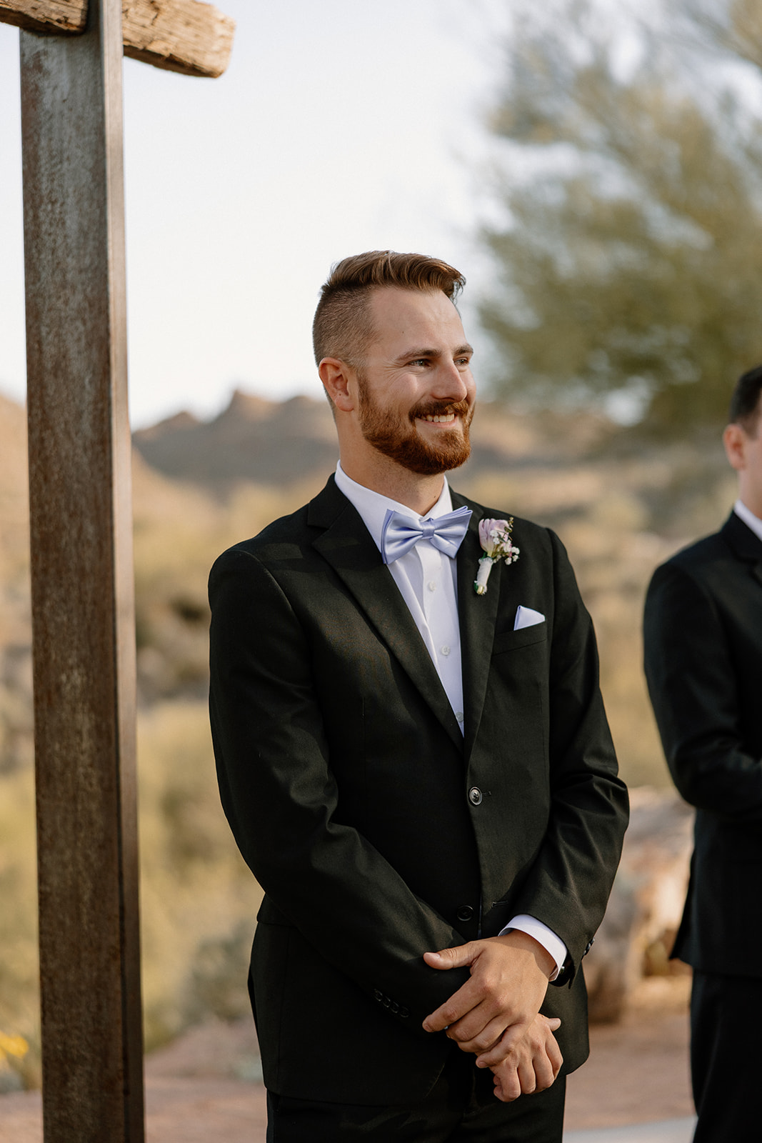 Groom watching the bride walk down the aisle with a smile at The Cove at Bartlett Lake wedding ceremony.

