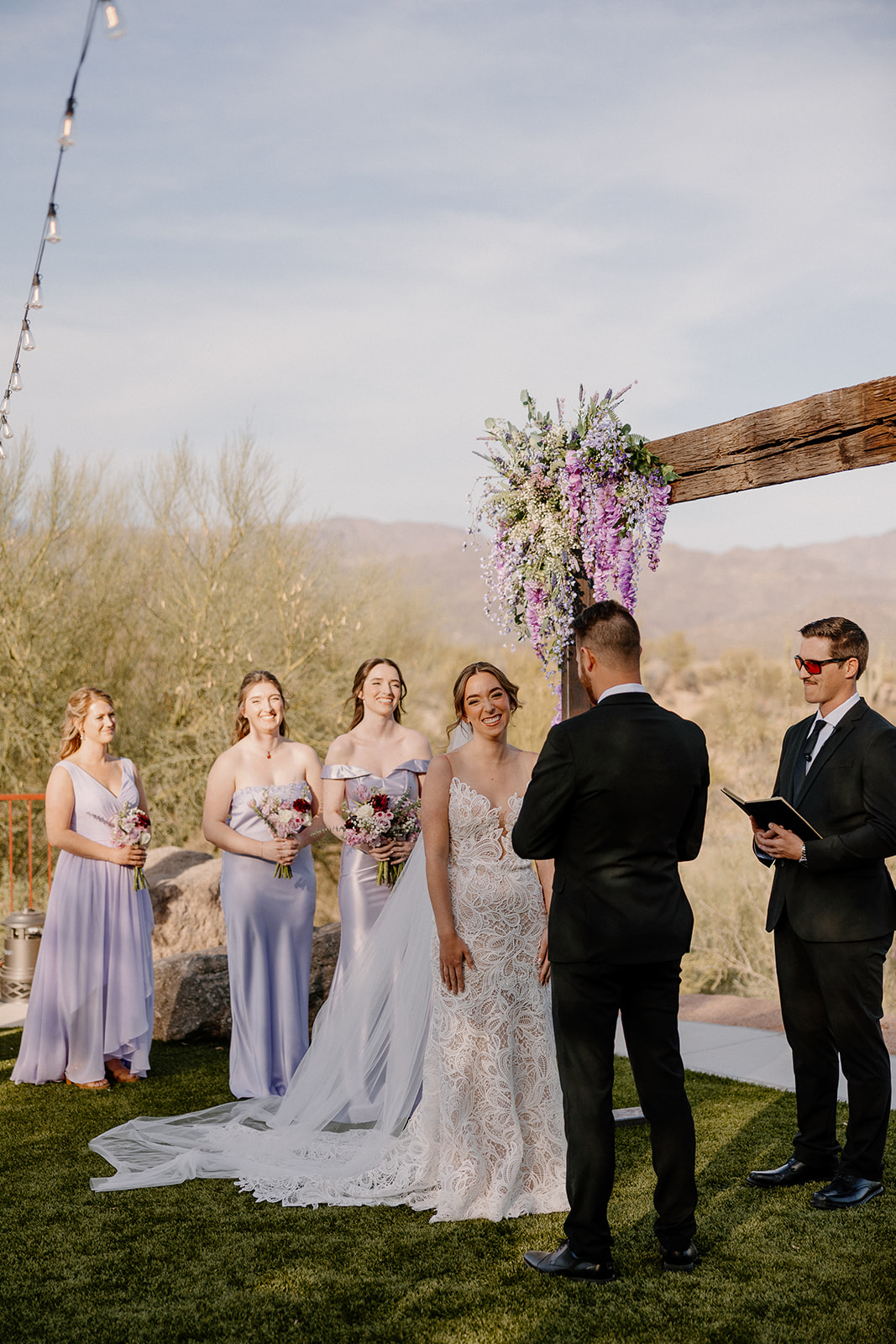 Bride smiling at her groom during outdoor ceremony under a floral arch at The Cove at Bartlett Lake wedding in Arizona.