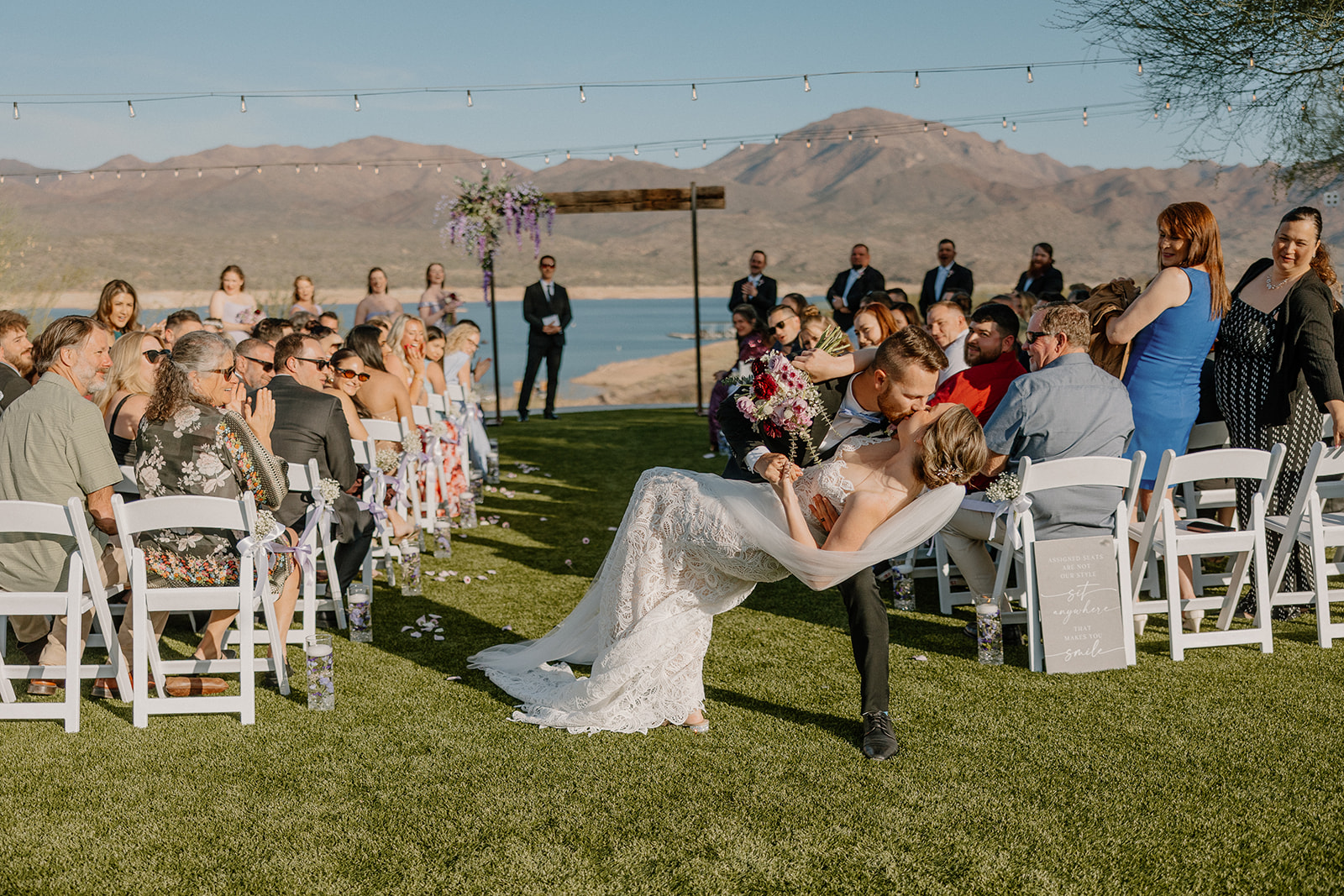 Groom dips bride for a kiss at the end of their ceremony surrounded by guests at The Cove at Bartlett Lake wedding.

