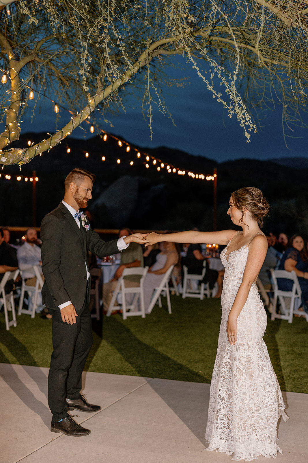 Romantic first dance moment for bride and groom beneath string lights at The Cove at Bartlett Lake wedding venue.

