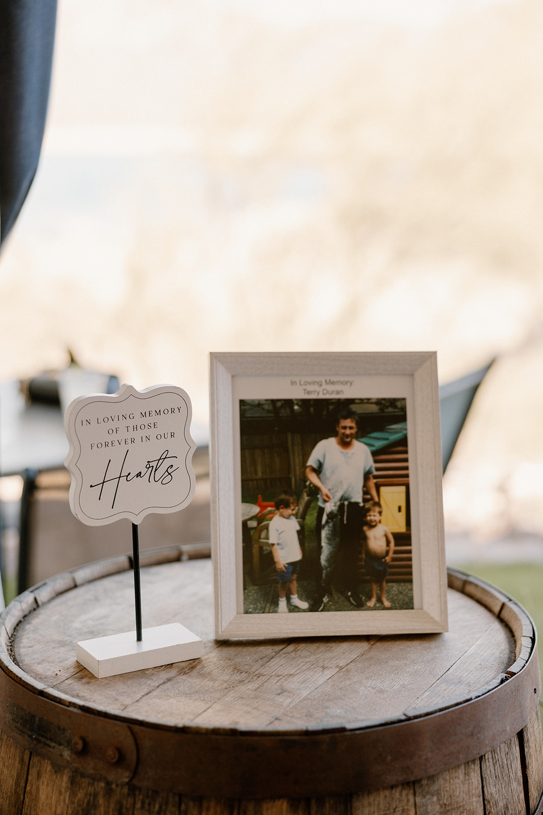 In loving memory table with framed photo and sign honoring lost loved ones at The Cove at Bartlett Lake wedding ceremony.

