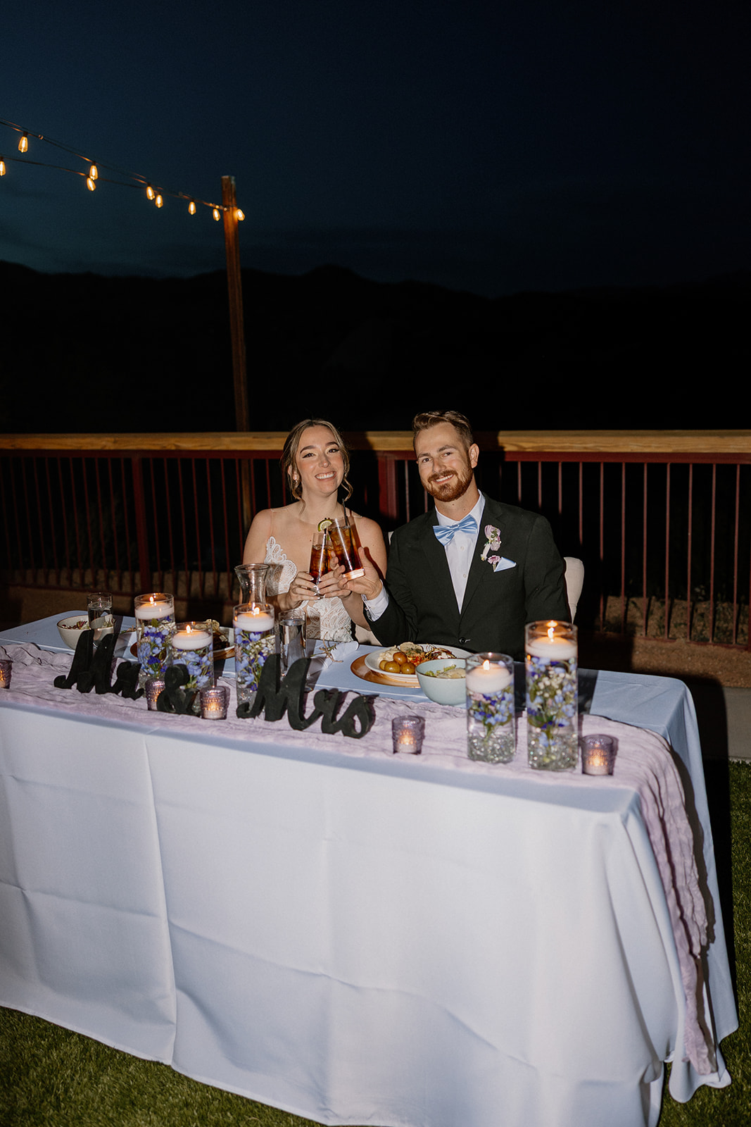 Bride and groom clinking drinks at their sweetheart table during dinner at The Cove at Bartlett Lake wedding reception.

