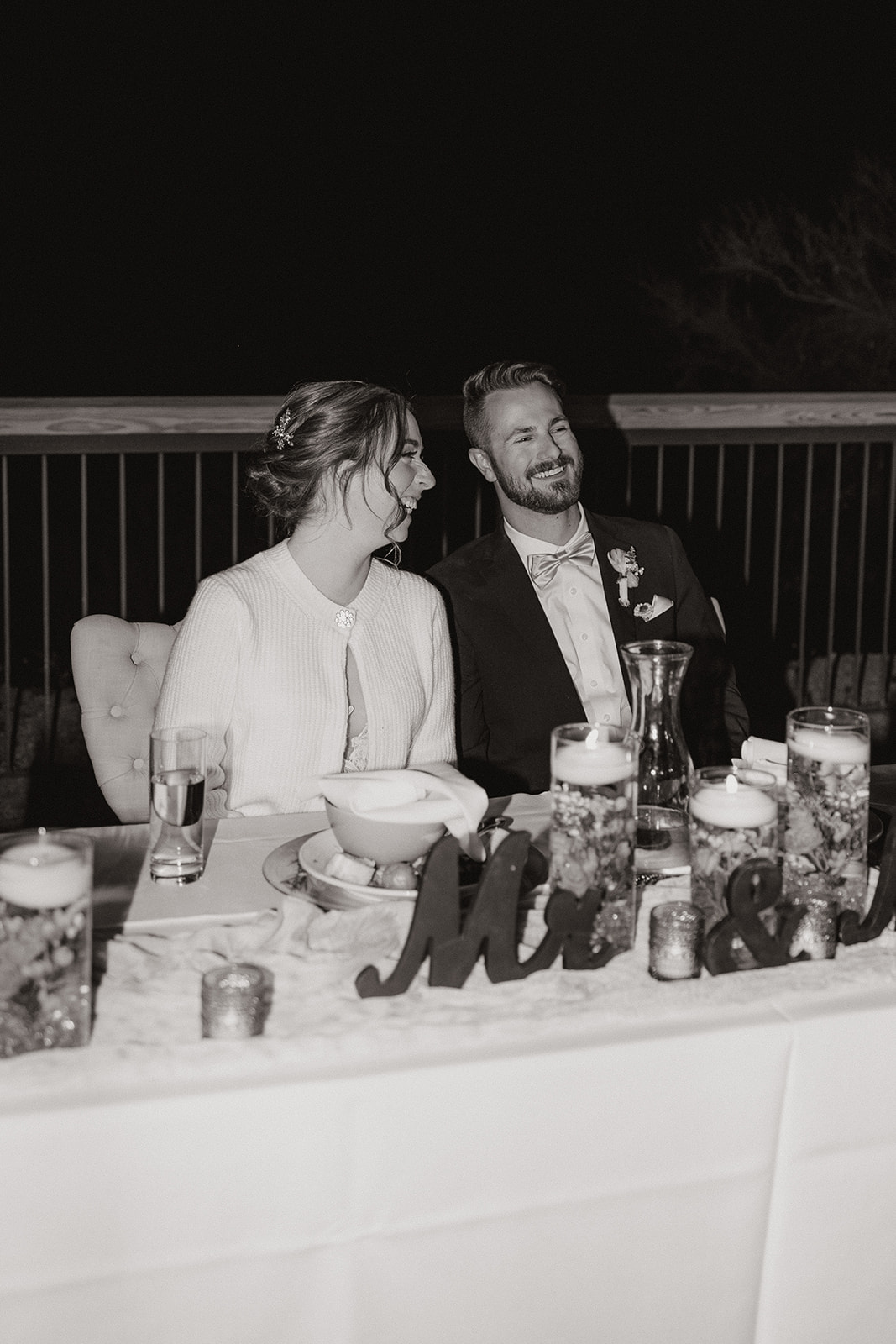 Bride and groom sharing a candid moment at their sweetheart table during The Cove at Bartlett Lake wedding reception.

