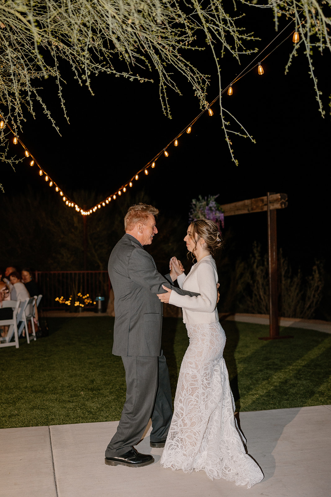 Bride dancing with her father under string lights at The Cove at Bartlett Lake wedding during an outdoor reception.

