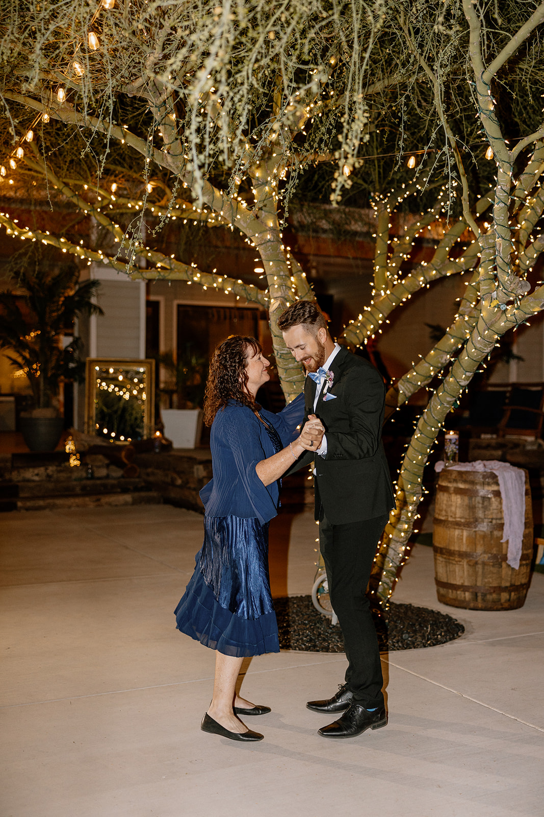 Groom dancing with his mother under fairy lights at The Cove at Bartlett Lake wedding reception.

