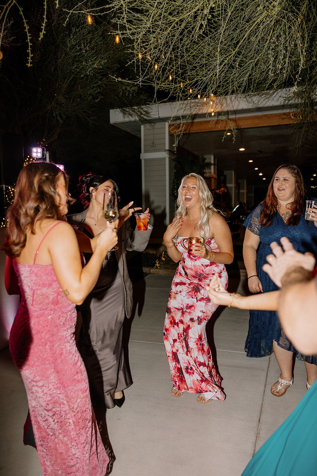 Women laughing and dancing in vibrant dresses during the reception at The Cove at Bartlett Lake wedding venue.

