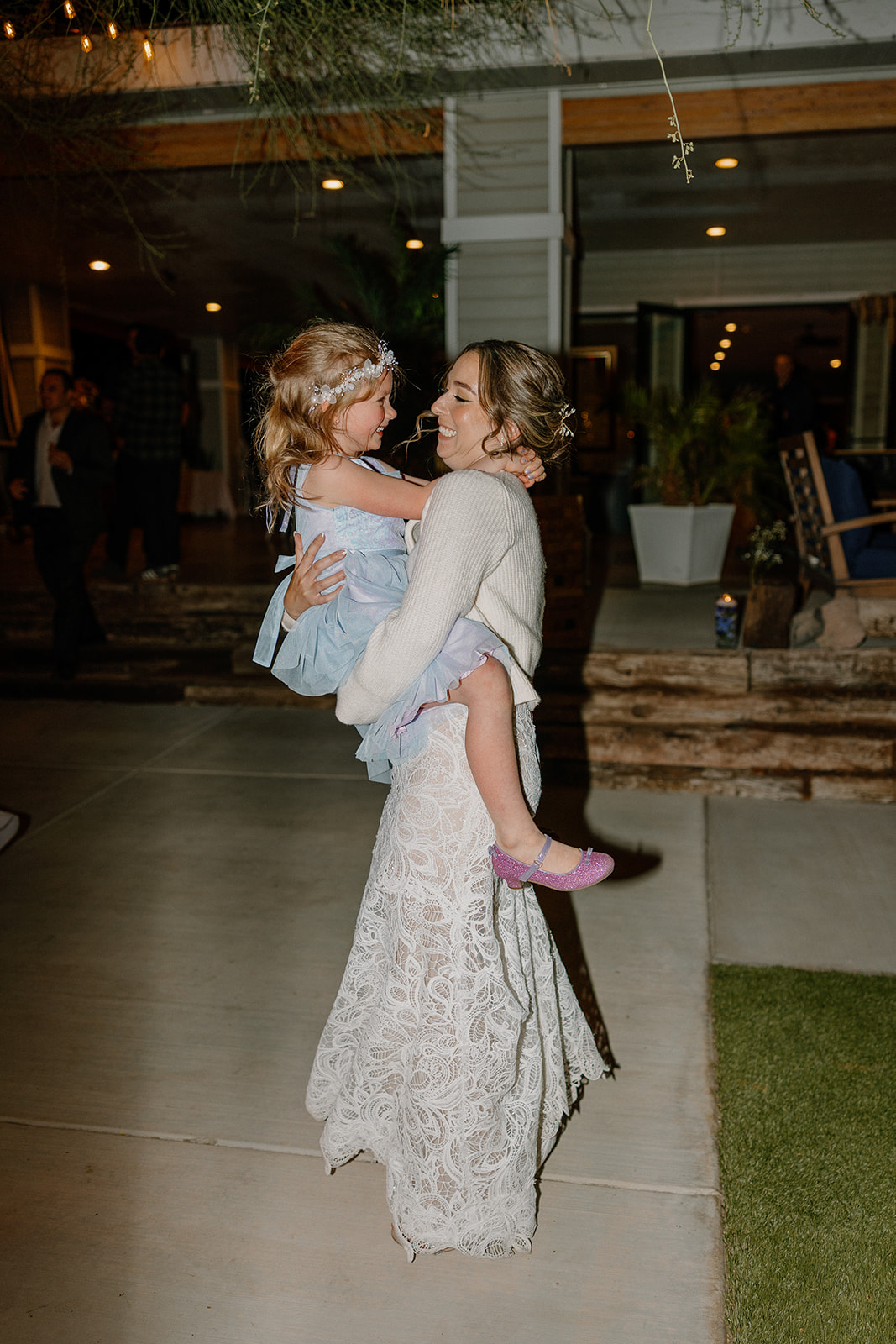 Bride holding a young flower girl during a candid dance moment at The Cove at Bartlett Lake wedding reception.

