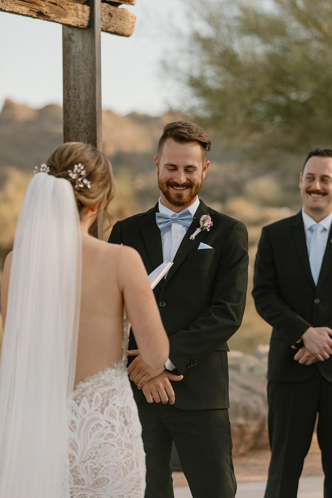 Groom smiling as he listens to the bride's vows during a romantic lakeside ceremony at The Cove at Bartlett Lake wedding.