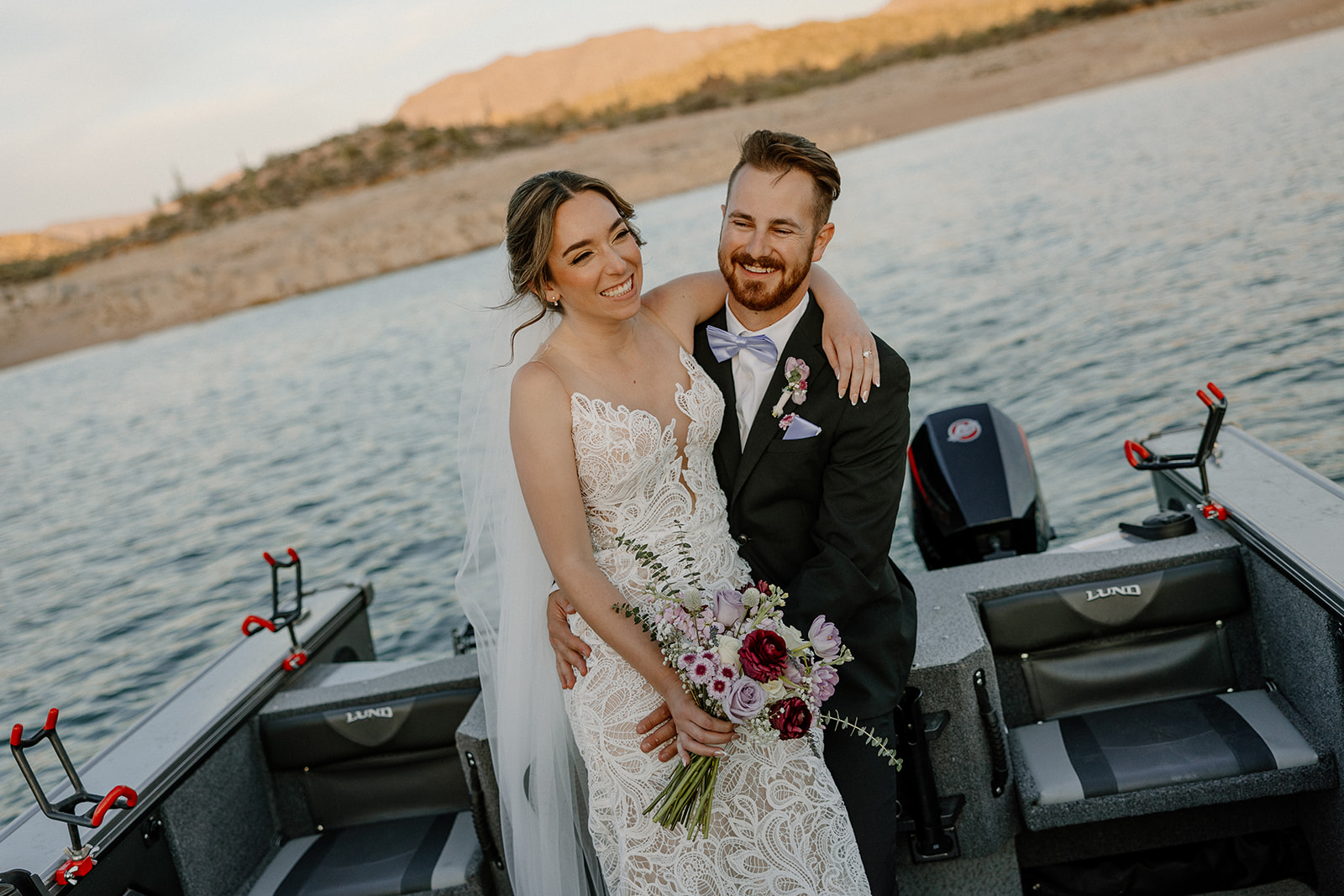Couple holding each other on a boat, grinning ear to ear during their The Cove at Bartlett Lake wedding portraits.
