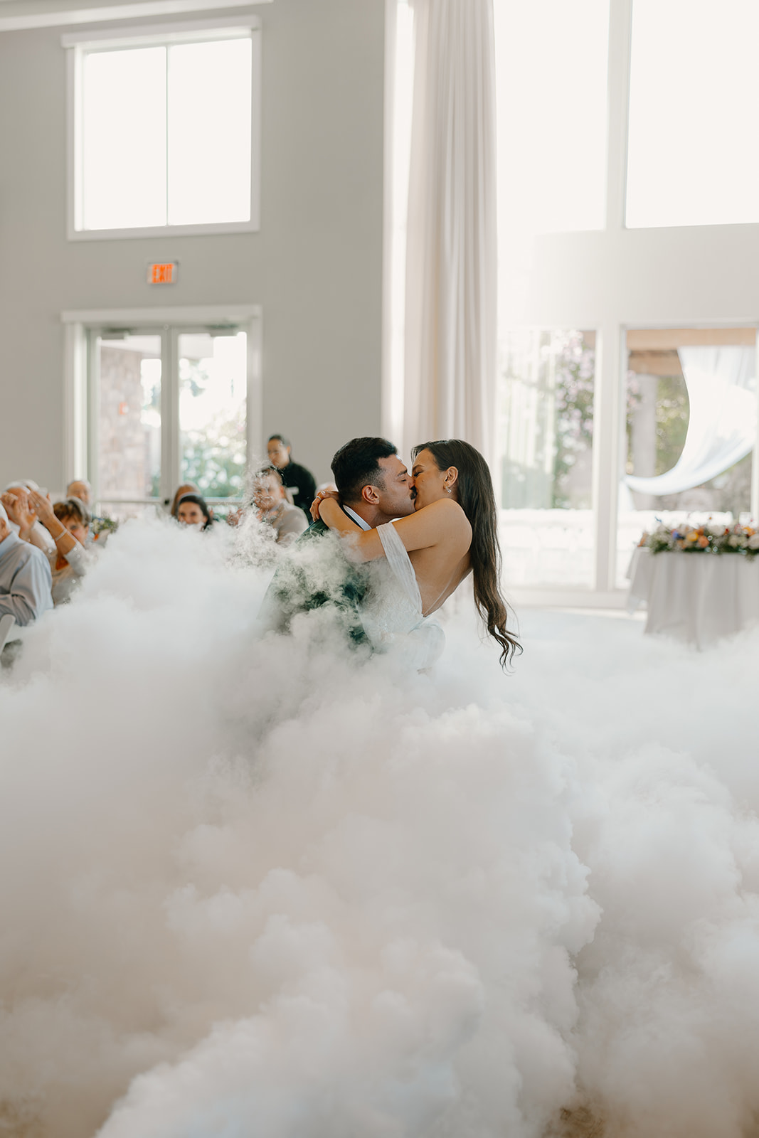 Newlyweds share a dreamy kiss while dancing in a cloud-like fog during their first dance at an Arizona wedding reception.

