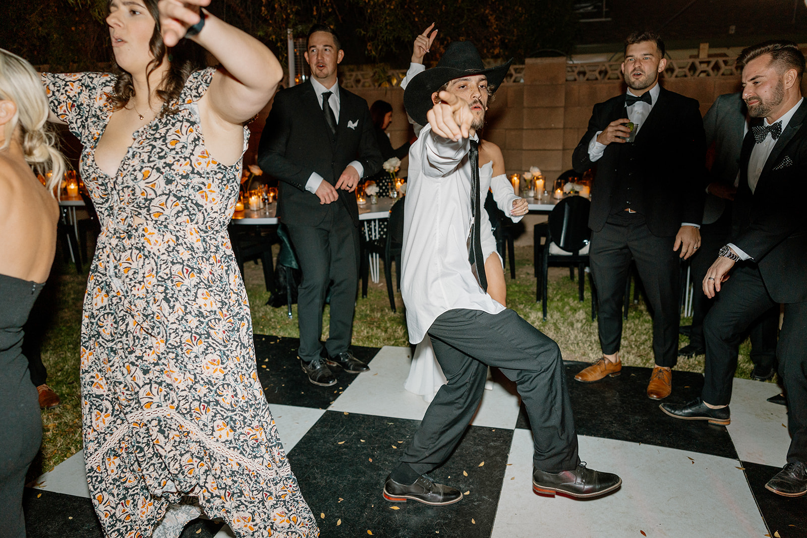 Guests hit the black-and-white dance floor with bold moves and big energy at a backyard-style wedding celebration.

