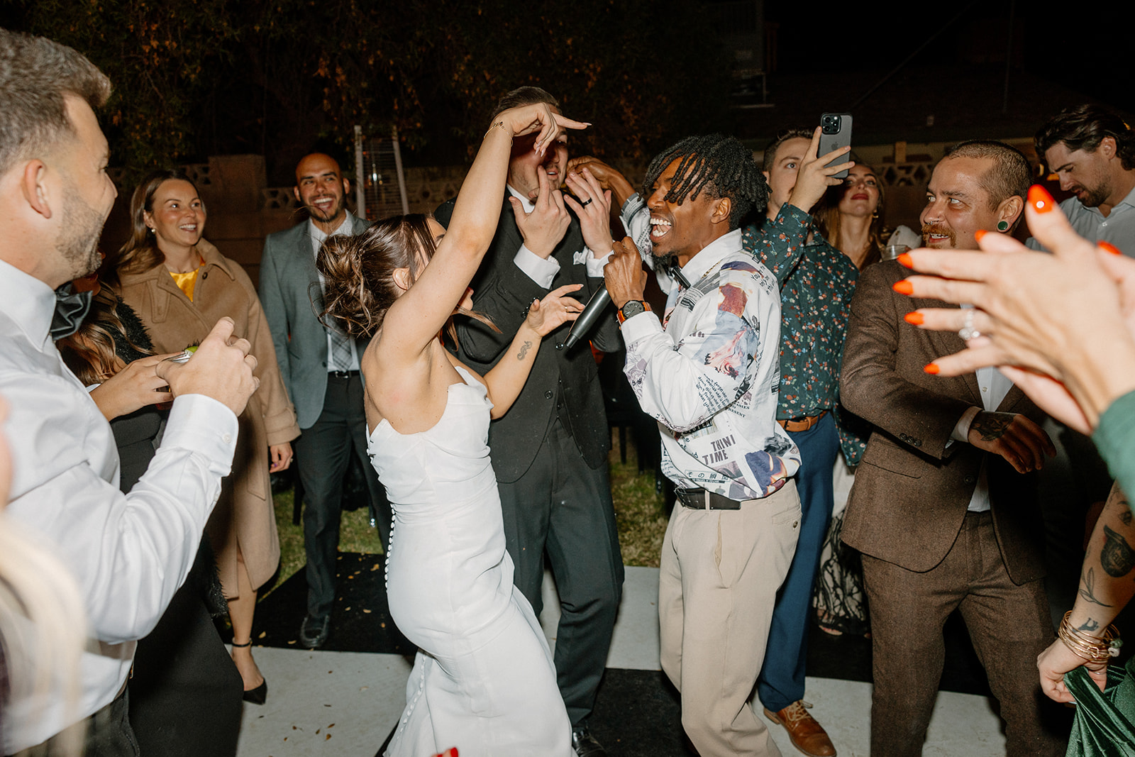 The bride dances with a live hype man surrounded by cheering guests on the black-and-white floor at an Arizona wedding reception.


