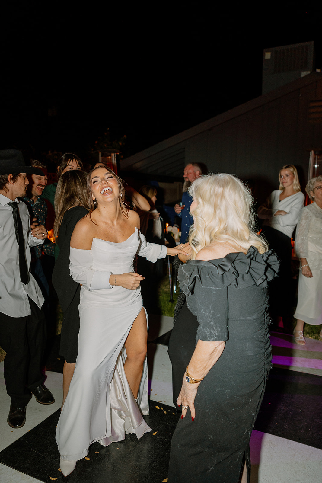 The bride laughs with a family member on the dance floor, both fully living in the moment at the evening reception.

