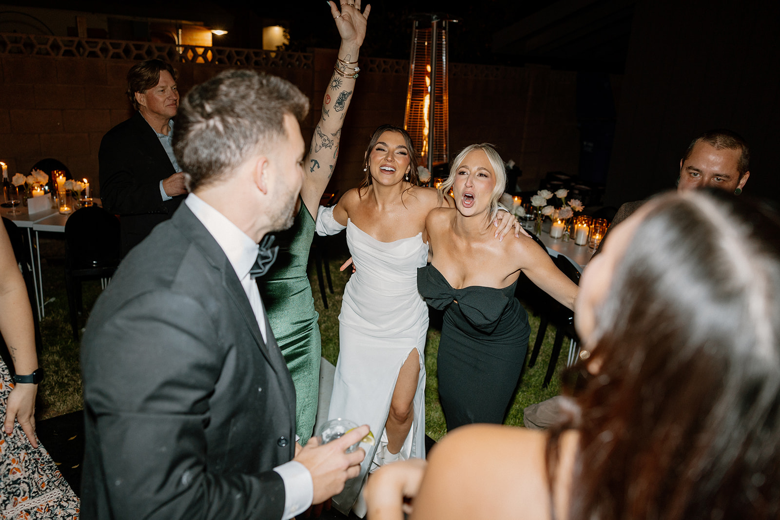 The bride and her friends sing at the top of their lungs during a high-energy dance moment at a backyard wedding reception.

