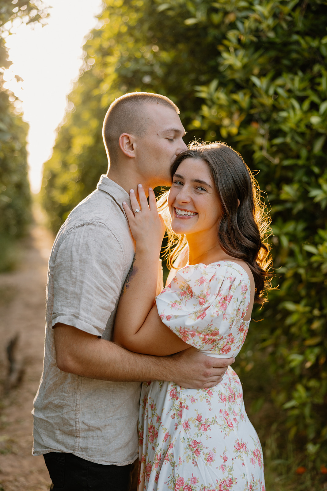 Man embracing woman while sun hits their faces in orchard