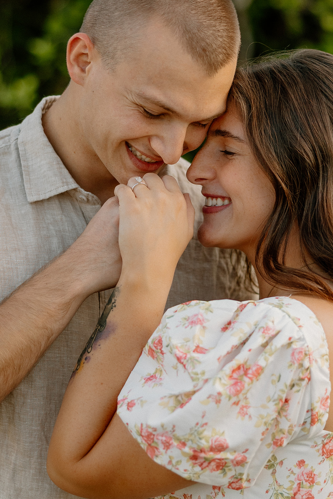 Couple cuddling up together holding hands in green orange orchard