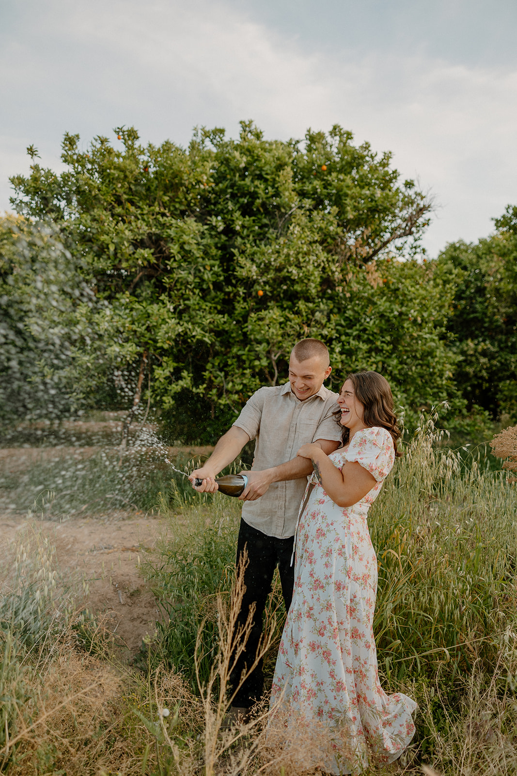 Engaged couple popping champagne to celebrate recent engagement