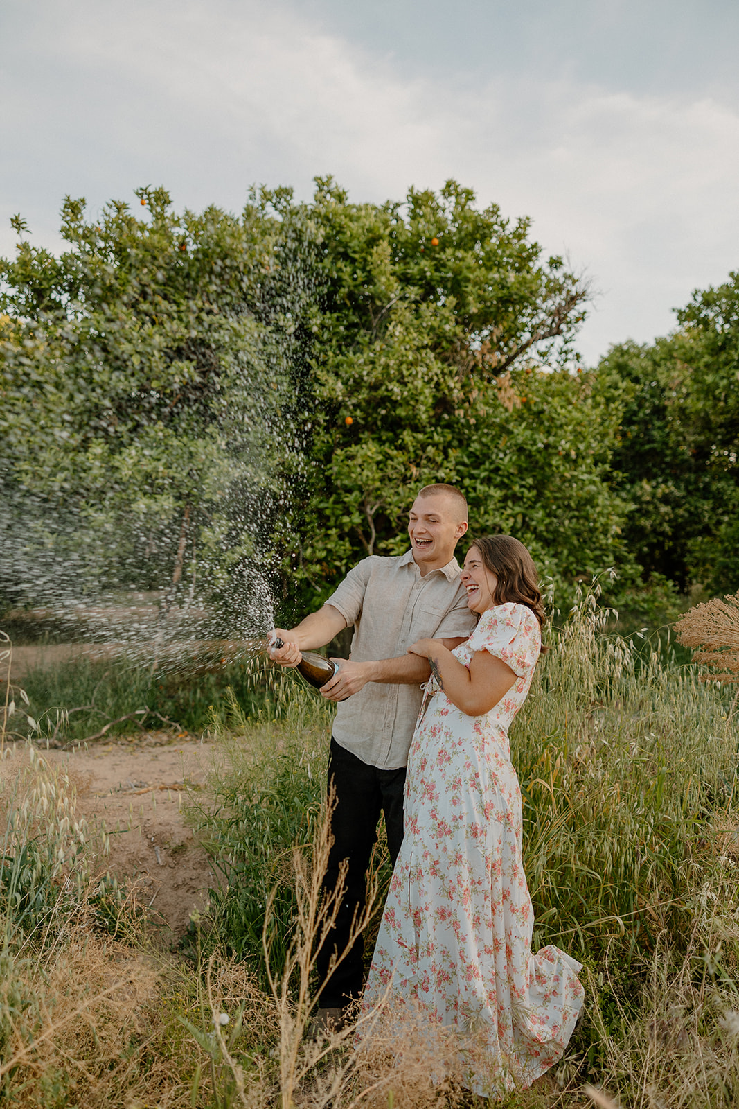 Champagne being popped at the end of orchard engagement photos