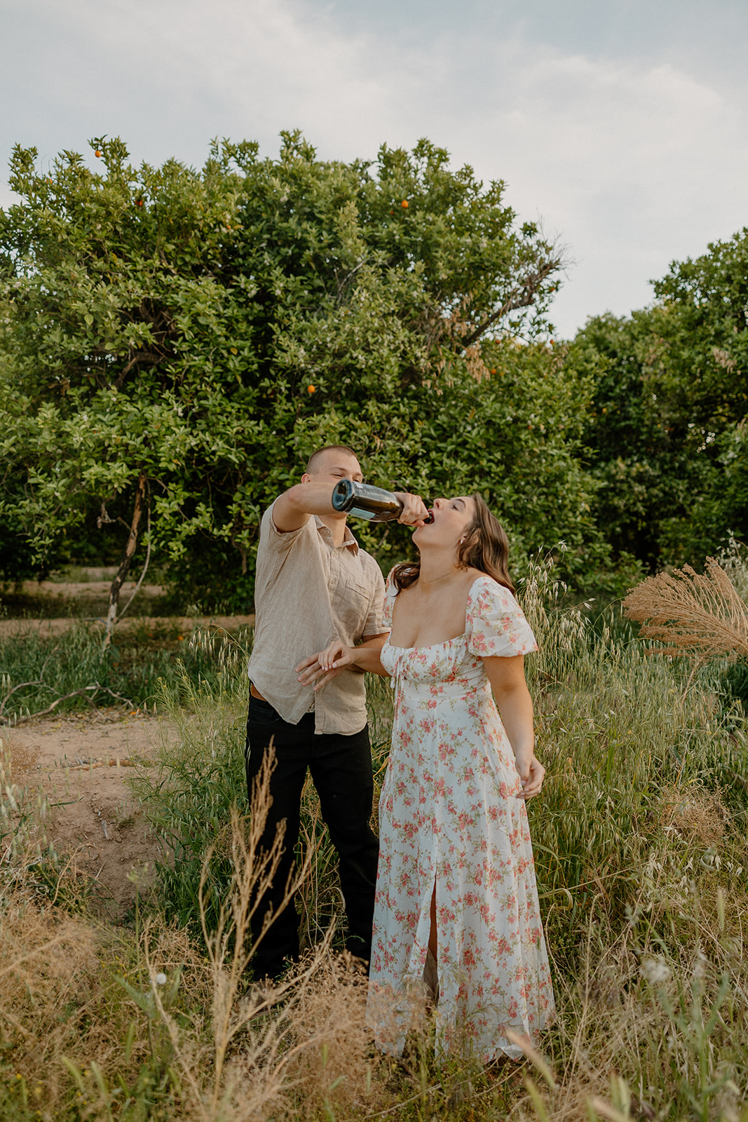 man pouring champagne into woman's mouth after popping champagne