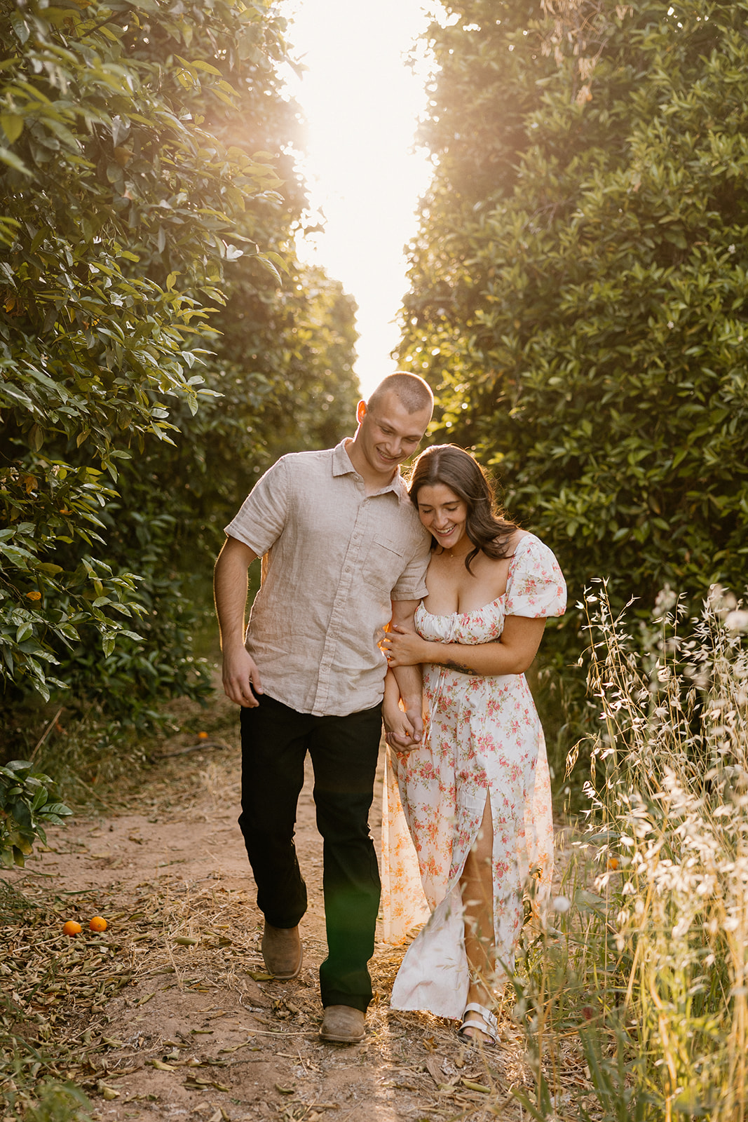 Couple walking through orchard together during golden hour photos