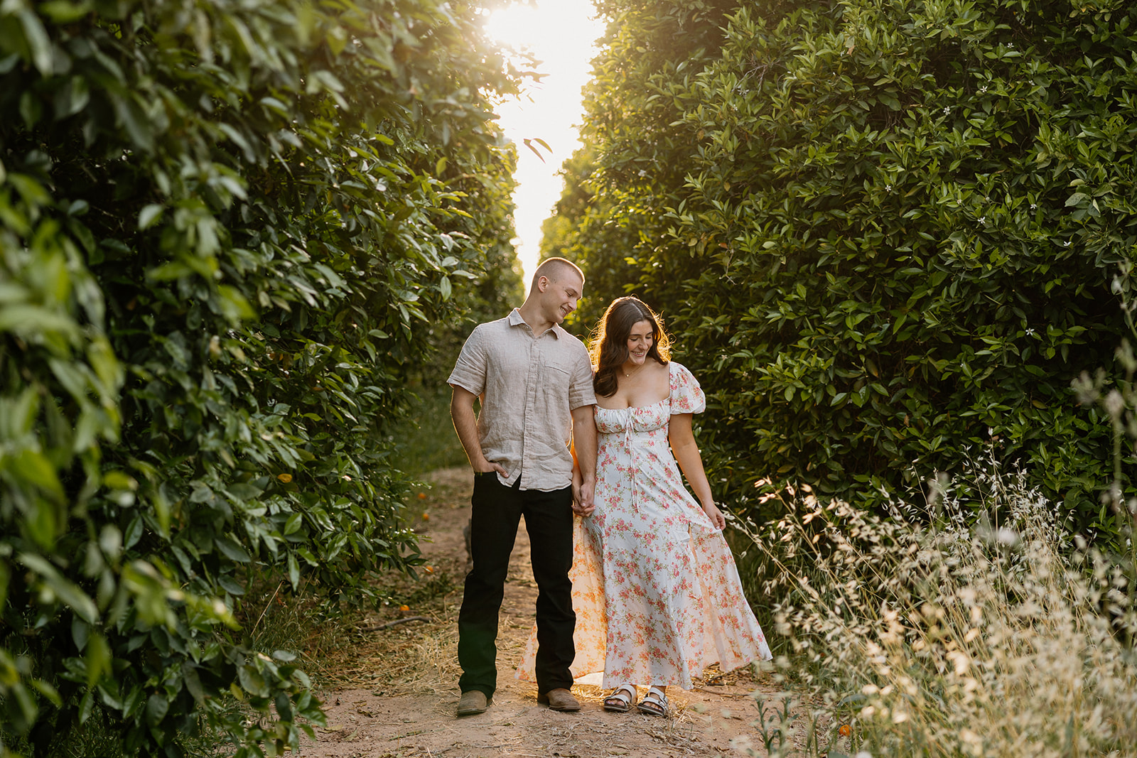 Woman fanning out dress while holding fiance's hand during engagement photos
