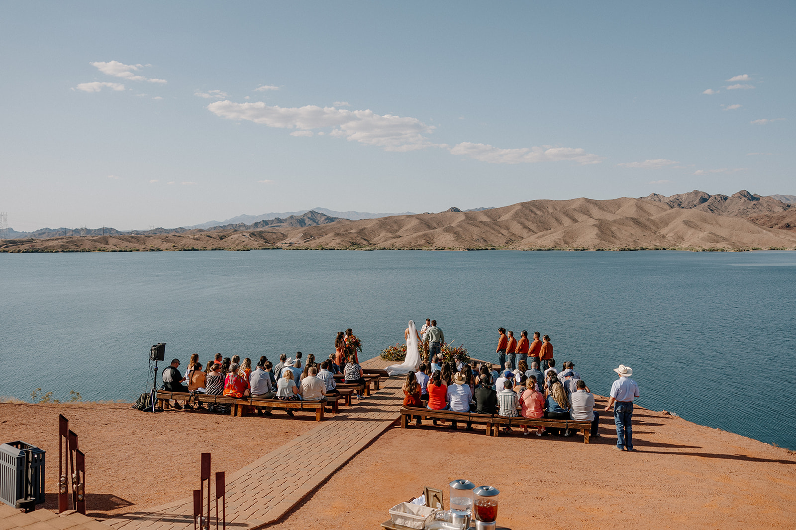 Guests watch a lakeside ceremony unfold from rustic wooden benches while the Arizona mountains and open sky set the stage—true magic at waterfront wedding venues in Arizona.