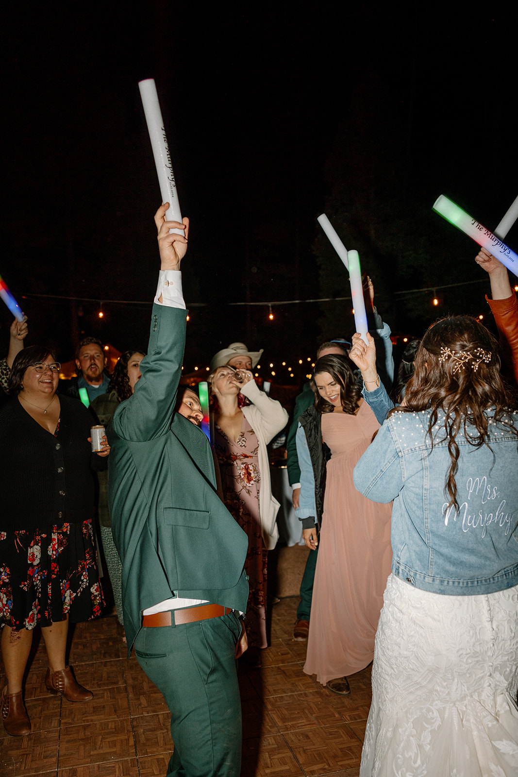 The bride and guests raise LED glow sticks during an epic nighttime celebration under the stars at an Arizona wedding reception.

