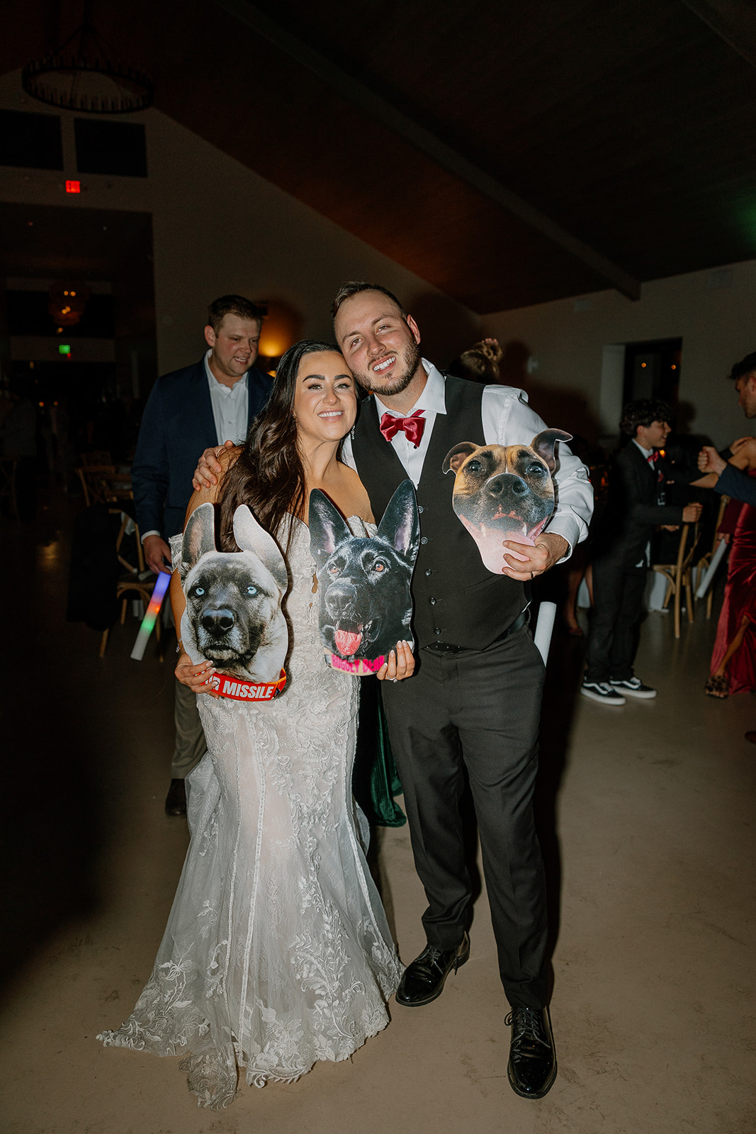 The bride and groom smile while holding oversized cutouts of their dogs during their Arizona wedding reception, adding a personal touch to the celebration.

