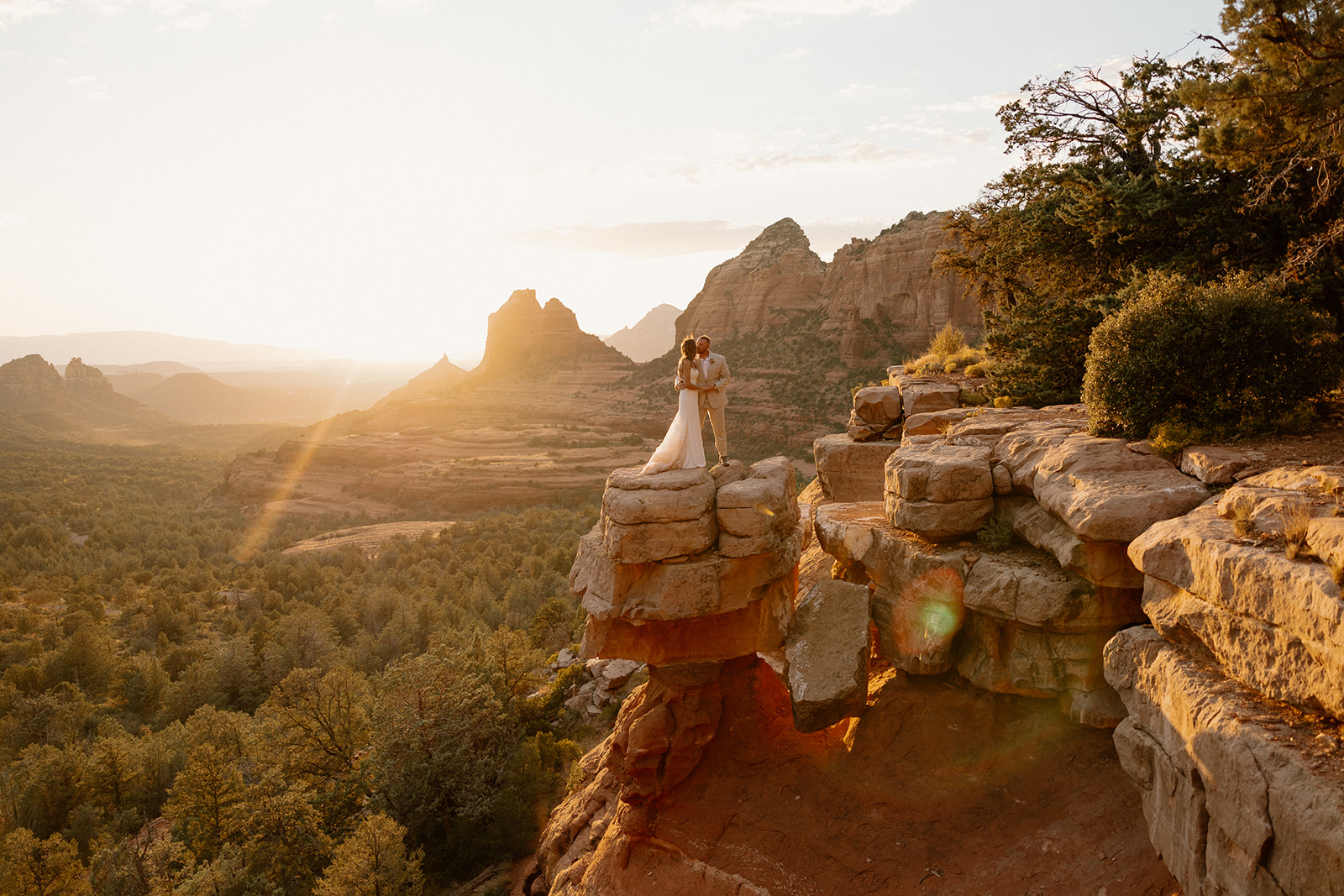Bride and groom standing on red rocks embracing after Arizona adventure