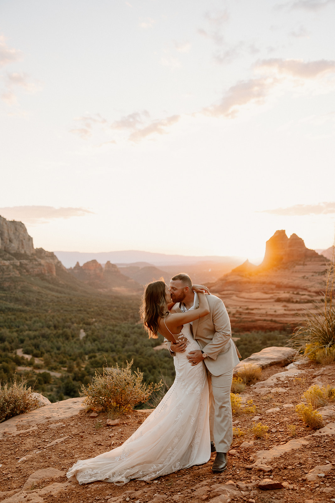 Bride and groom kiss at sunset on top of Arizona red rocks