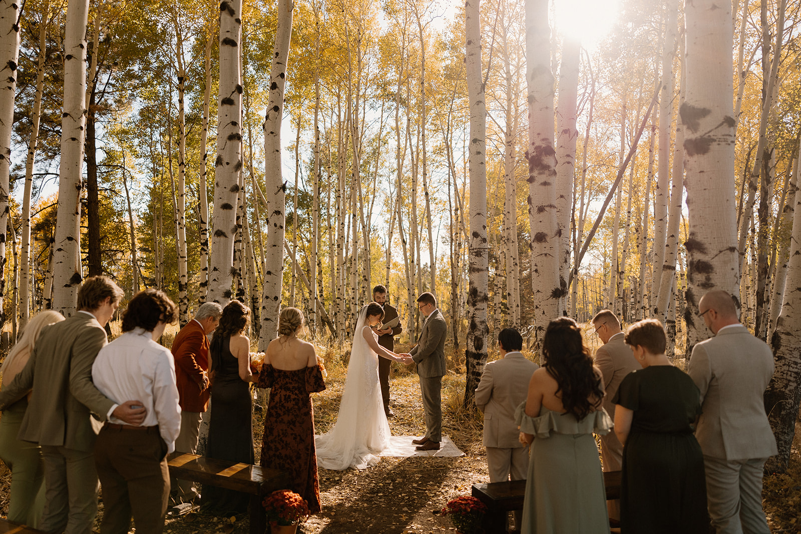 Arizona elopement ceremony with the couple exchanging vows in a glowing forest of tall aspen trees.