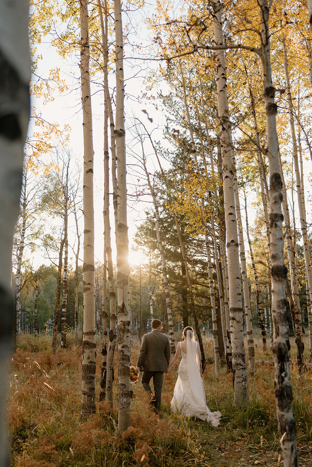Bride and groom walking hand in hand through forest after Arizona adventure elopement