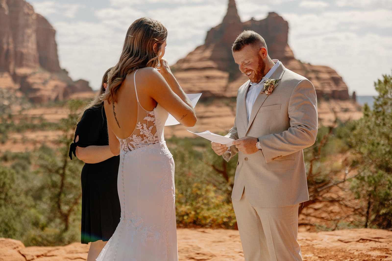 Intimate moment during a vow exchange in front of Bell Rock, with groom wedding attire styled in a light beige suit and open-collar white shirt.