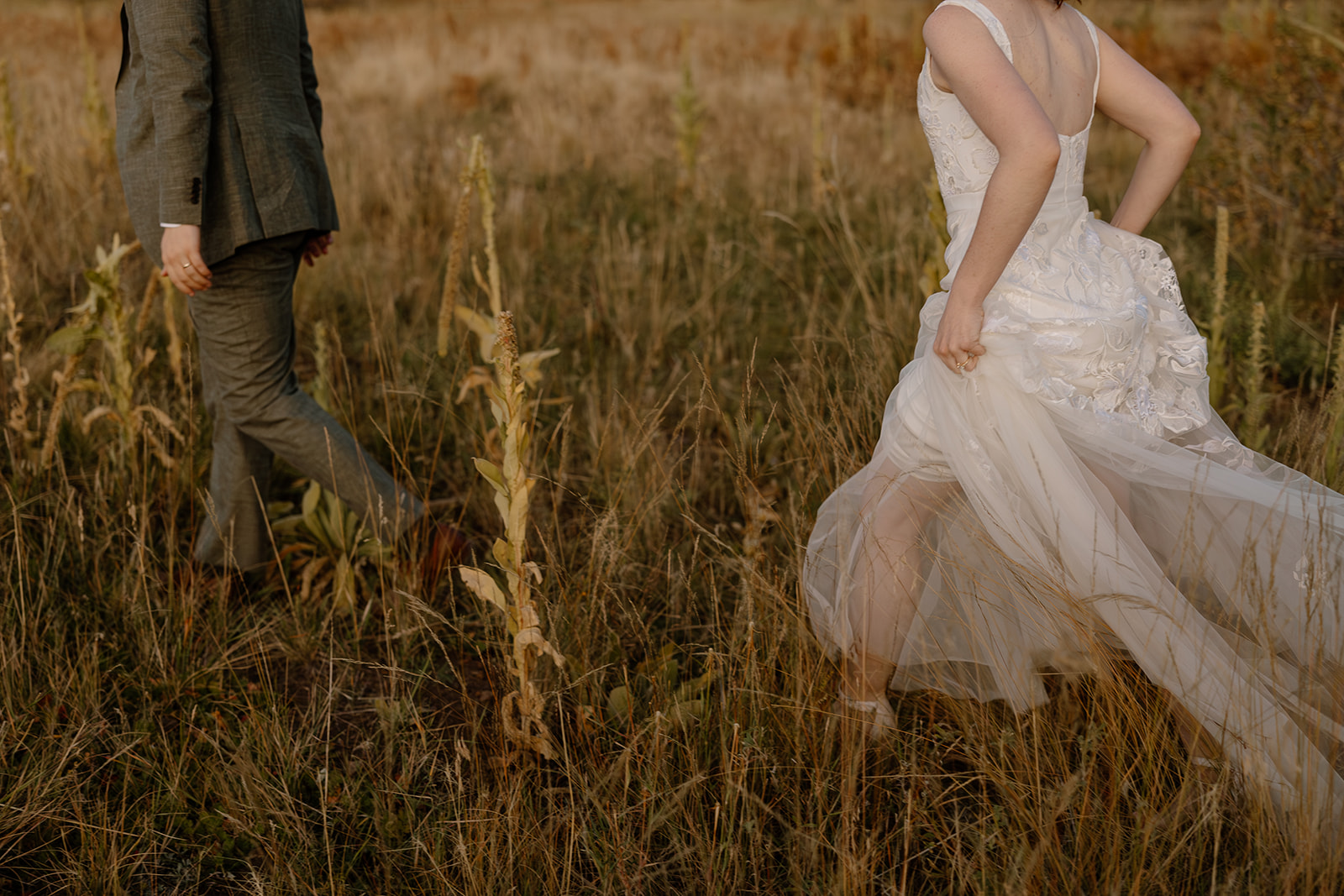 Couple running through tall grass after wedding ceremony