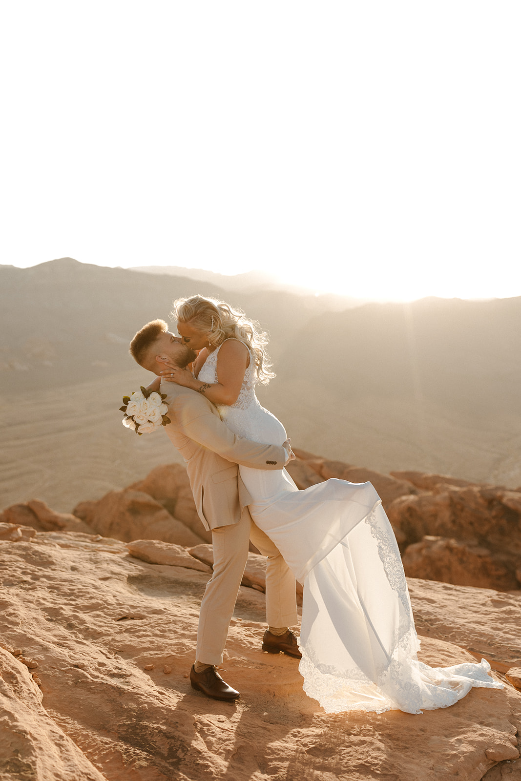 Groom dipping bride into a kiss on a glowing cliffside at sunset during their adventurous Arizona elopement.