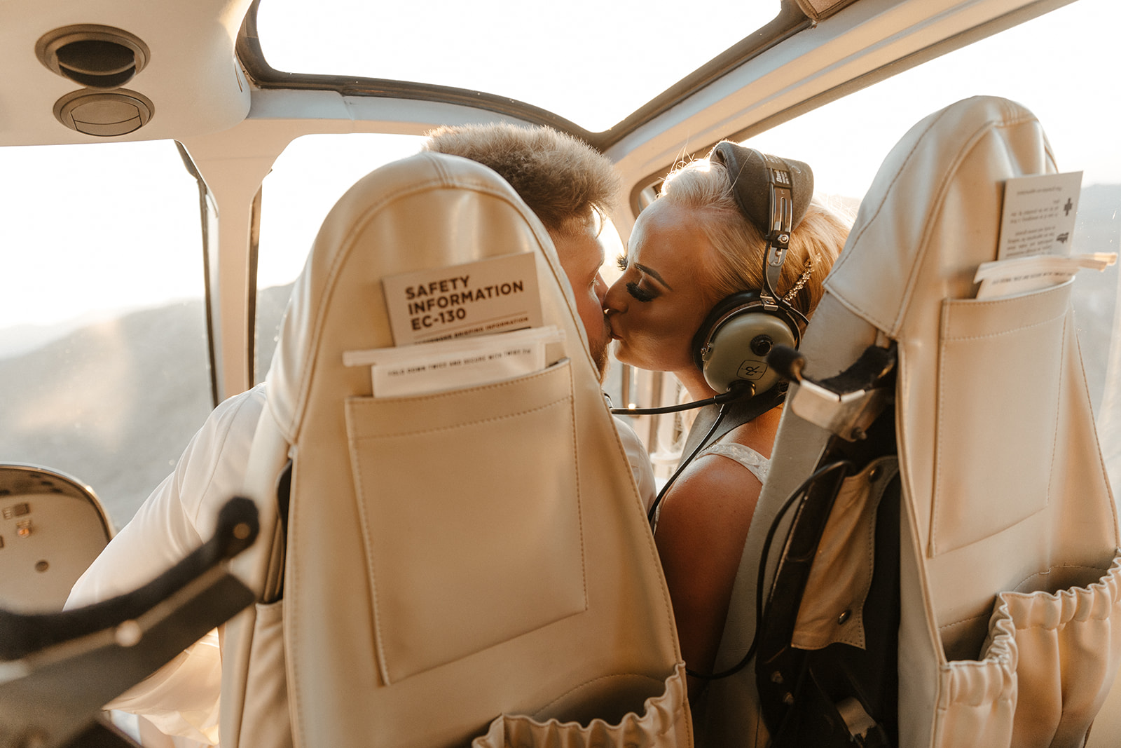 Bride and groom sharing a quiet moment and a kiss mid-flight in a helicopter after their adventure elopement.