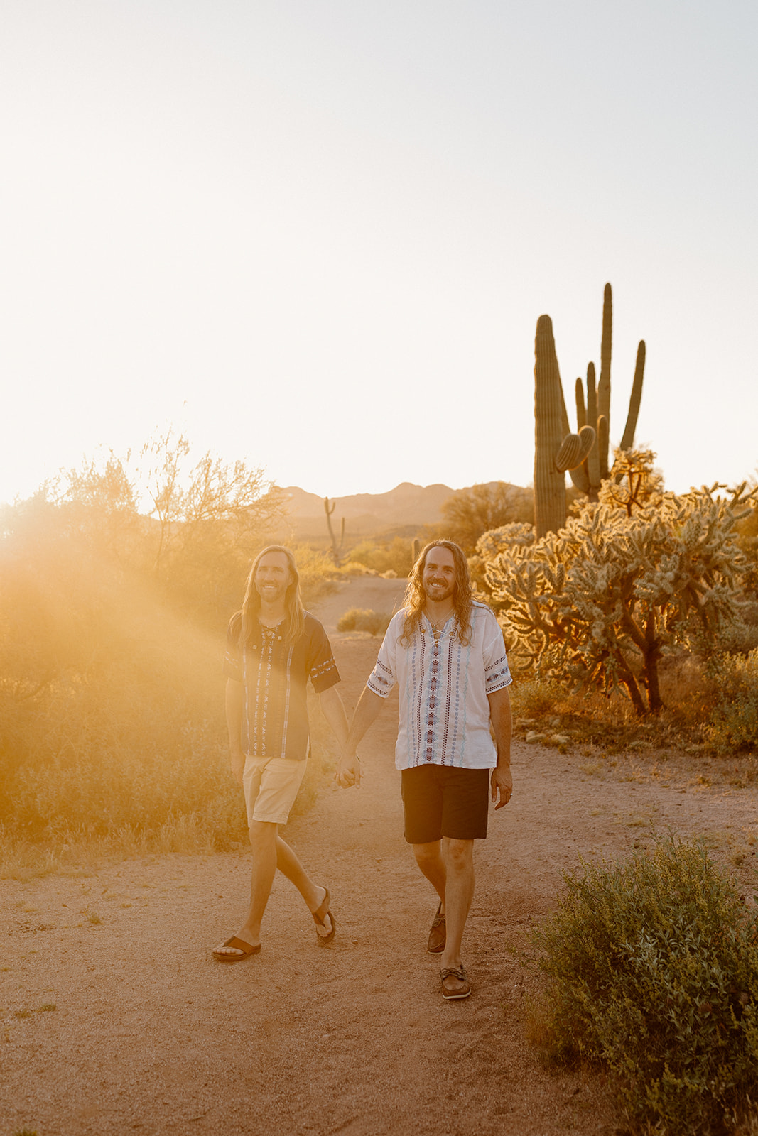 Newly married grooms walking hand in hand through Arizona desert at sunset