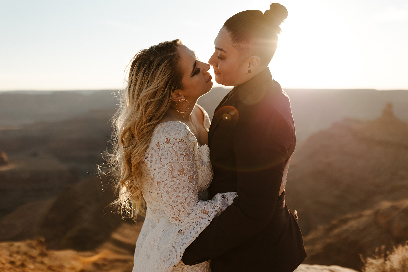 Sun-drenched embrace at a canyon overlook, couple leaning in with soft smiles just after eloping.
