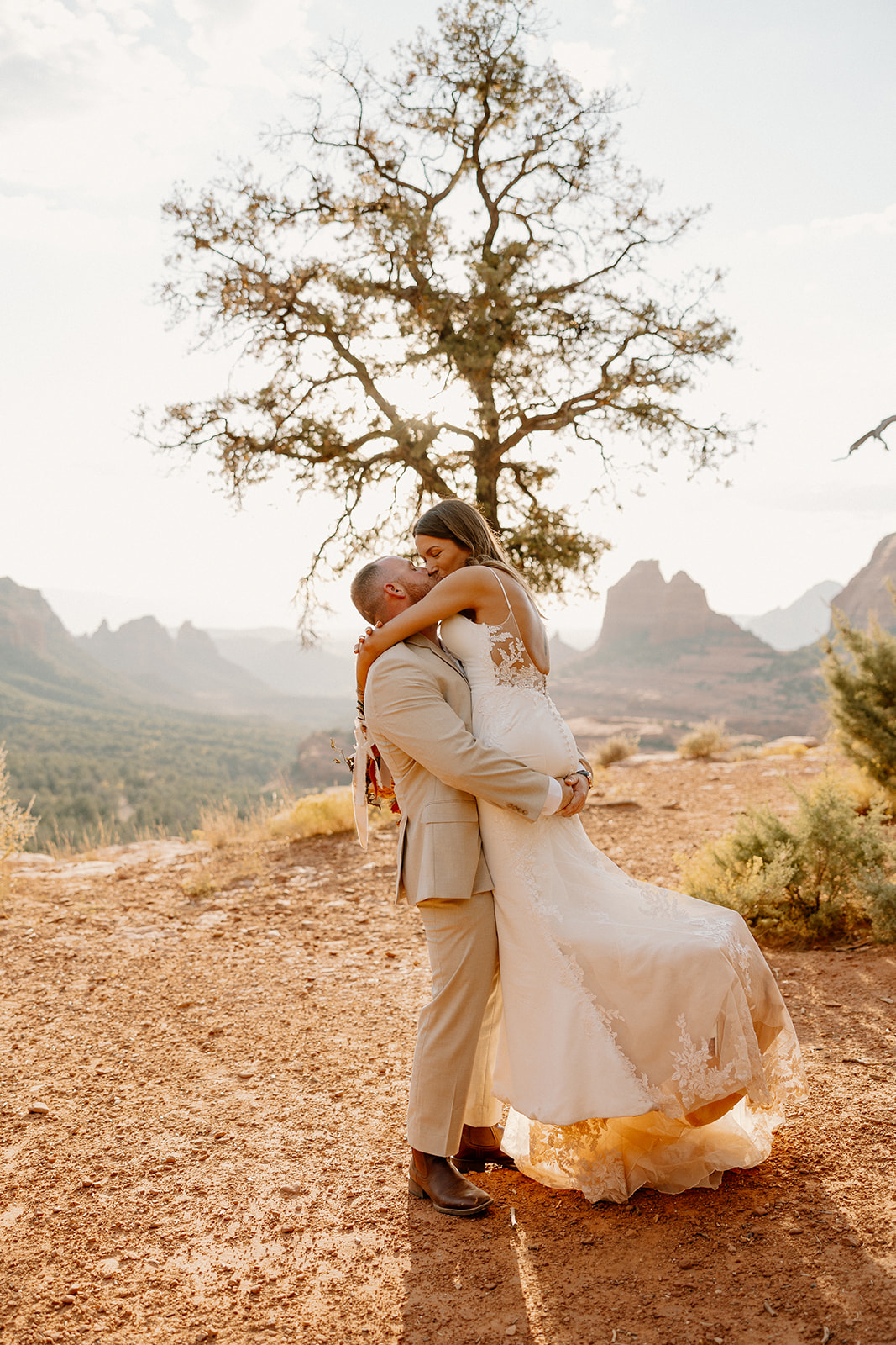 Emotional post-ceremony embrace in the desert, groom lifting bride as the sun sets—capturing a joyful moment after figuring out how to tell your family you're eloping.

