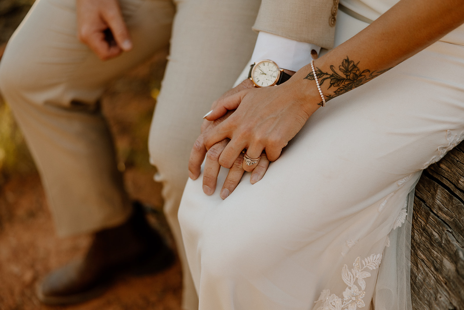 Detail shot of couple’s intertwined hands, showing wedding bands, tattoos, and a soft touch—symbolizing intimacy after deciding how to tell your family you're eloping.